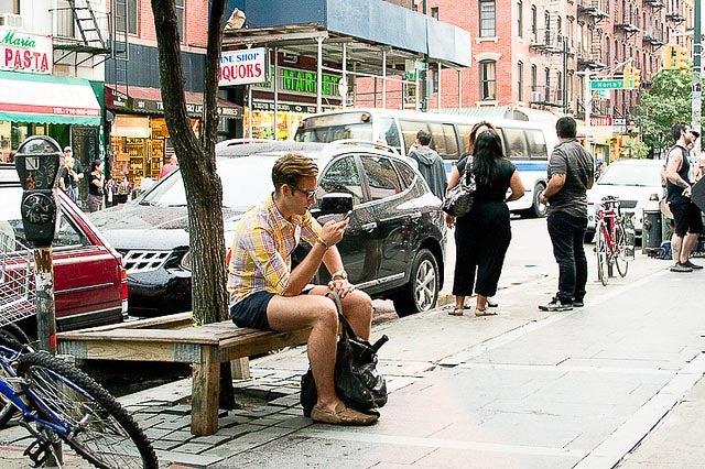 Man sitting on a city bench on his phone. 