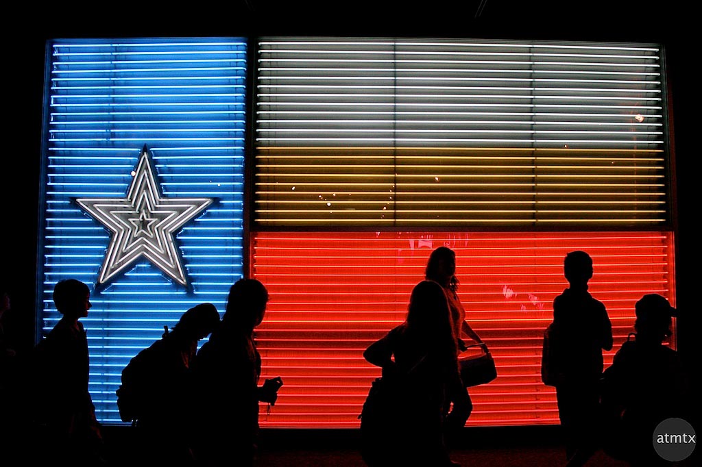 People in front of neon Texas flag