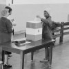Photograph showing a young African American woman casting her ballot. 