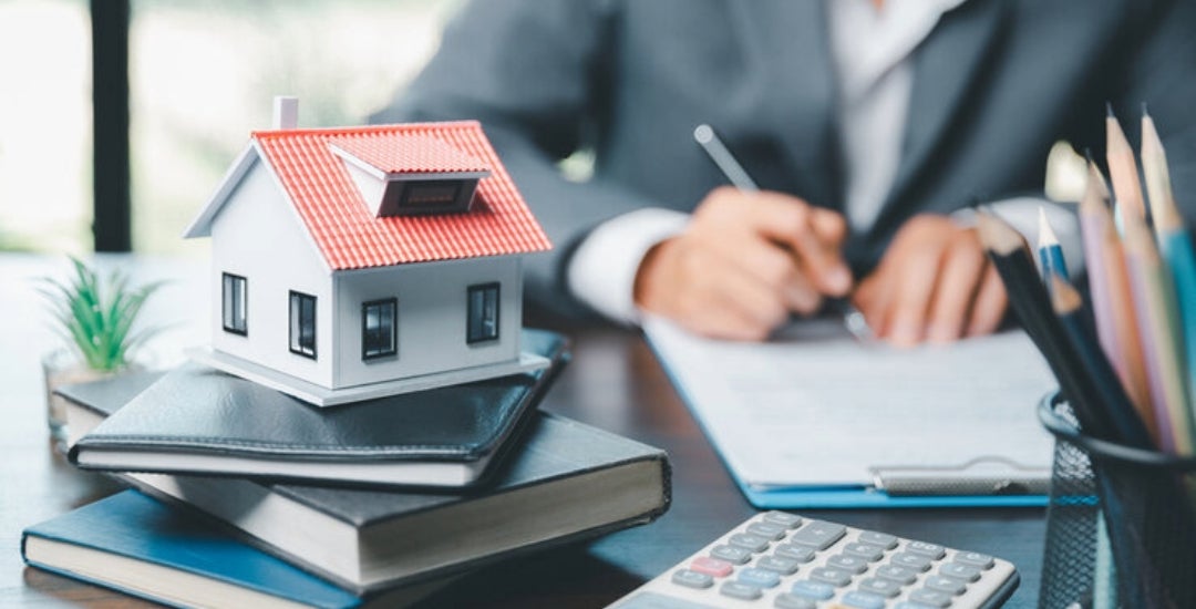 A business person prepares documents related to a house property.