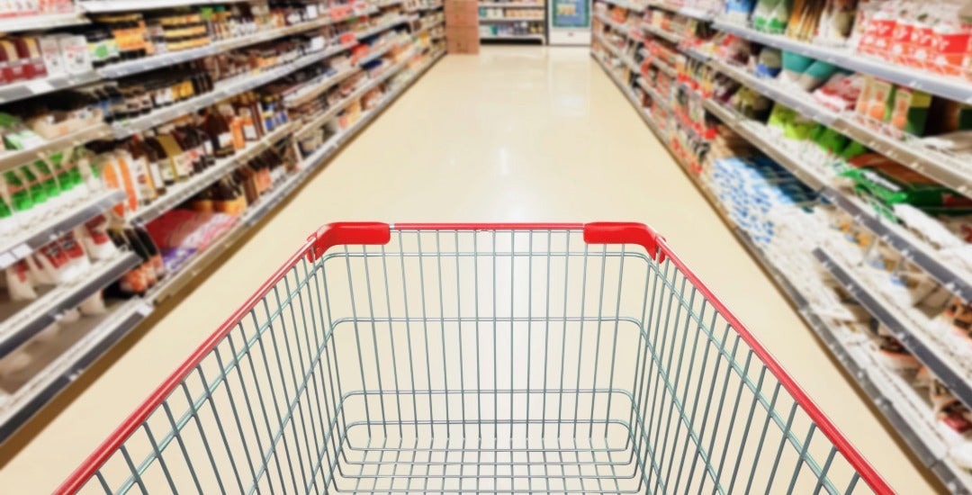 An empty grocery cart in a supermarket aisle.