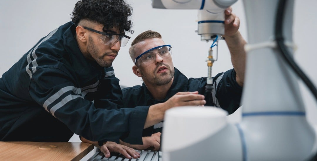 Students work on a robotic arm in a technical workshop.