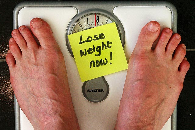 Man on a scale saying "Lose weight now!"