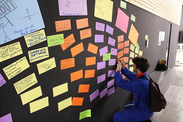 Man writes on colorful Post-it notes on a wall