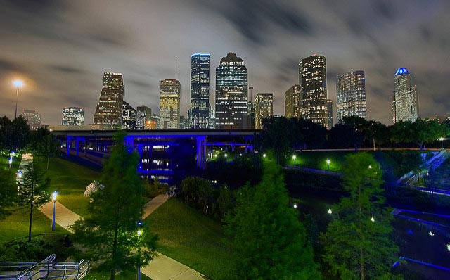 Blue lights under the bayou bridges in Houston with the skyline in the background
