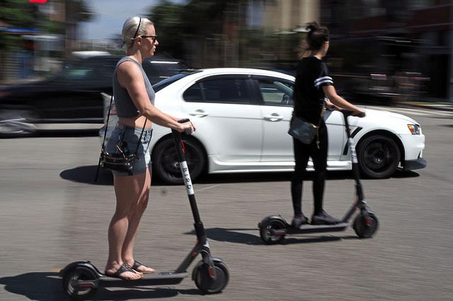 Women riding Bird electronic scooters