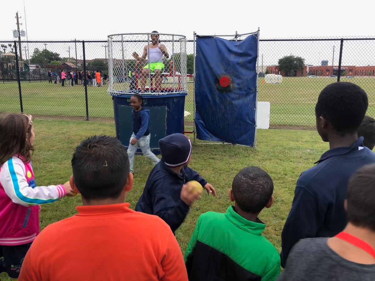 A school administrator sits in the dunk tank as kids throw balls