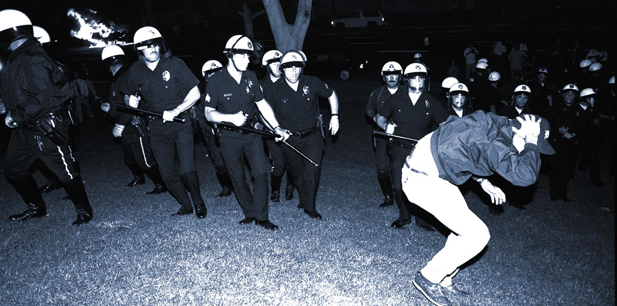LAPD officers confront a protestor on the south lawn of City Hall while a police car burns during night one of the Rodney King Riots on April 29, 1992, in Los Angeles, California..