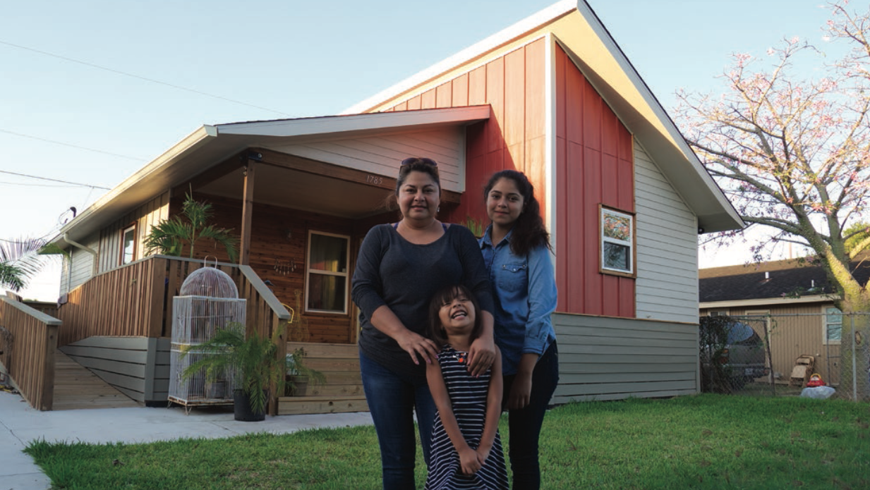 A family stands in front of a completed Rapido house. Image via buildingcommunityWORKSHOP.