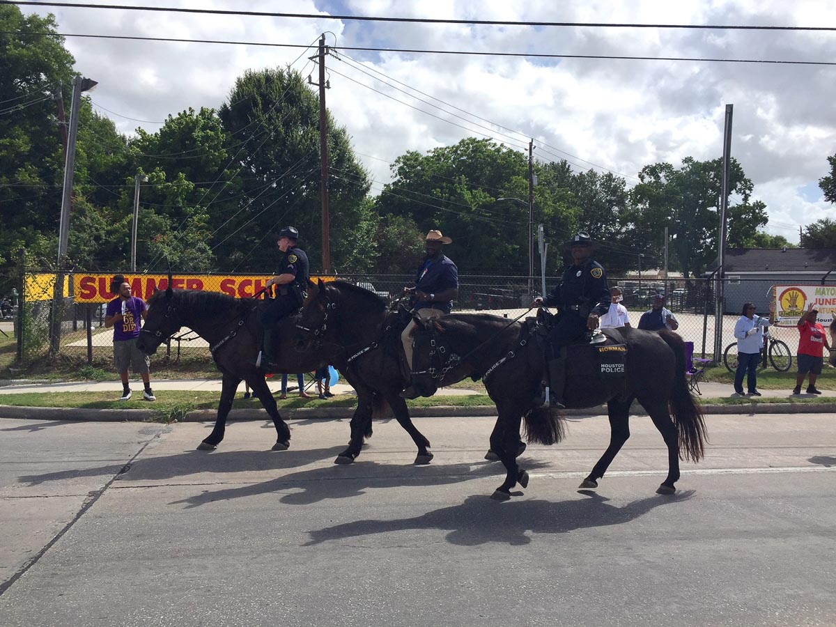A city council member rides on horseback with two policeman in the Juneteenth parade
