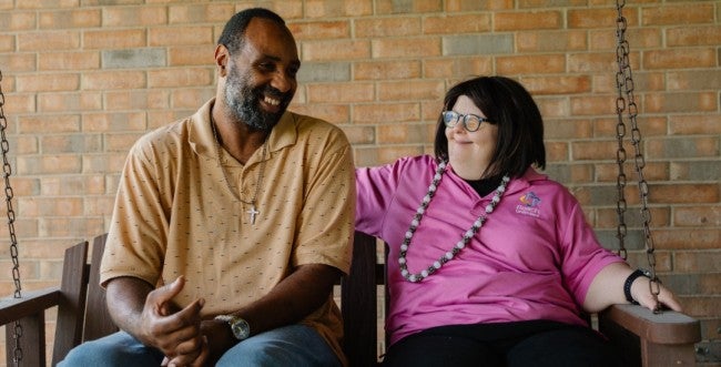 Two people share a moment together on a patio swing.