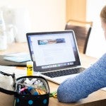 A girls works on a laptop computer.