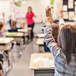 Students raising their hands in a classroom