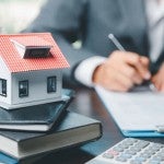 A business person prepares documents related to a house property.