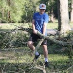 Person moving fallen tree branch after Hurricane Beryl