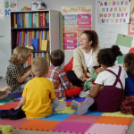 An early elementary school teacher sits with her class.