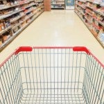 An empty grocery cart in a supermarket aisle.