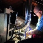 BakerRipley quality assurance manager Jacob Smith tests the ventilation of a gas furnace in the flue.