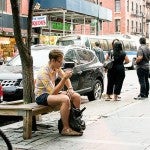 Man sitting on a city bench on his phone. 