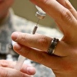 Man pulling vaccine from vile into syringe. 