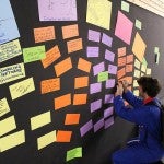 Man writes on colorful Post-it notes on a wall