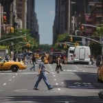 Man crossing the street with taxis in the background