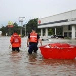 Men wading through water with a boat