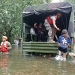 Man helping woman into a truck during a flood