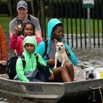 Three women being rescued by boat by two men during a flood