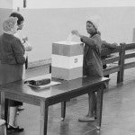 Photograph showing a young African American woman casting her ballot. 