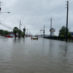 Men walking through floodwaters with a boat