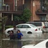 Man helping two children wade through flood water