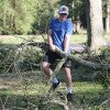 Person moving fallen tree branch after Hurricane Beryl