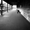 Black and white photo of a man waiting for a train