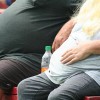 Two extremely overweight people sitting on a bench outside