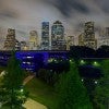 Blue lights under the bayou bridges in Houston with the skyline in the background