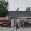 Man walking through floodwaters in front of business