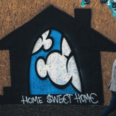 Man walking by graffiti that says Home Sweet Home