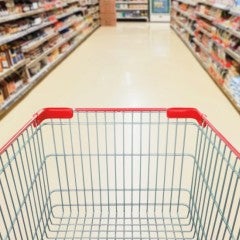 An empty grocery cart in a supermarket aisle.