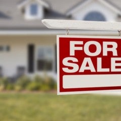 A single-story home with a "For sale" yard sign out front.